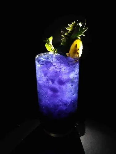 Purple cocktail with ice in a highball glass