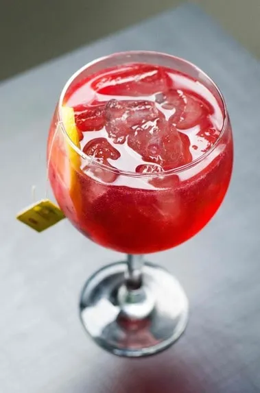 Red cocktail with ice and straw in a sharing glass