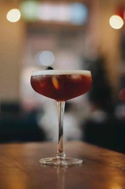 Deep red cocktail in a coupe glass on a bar